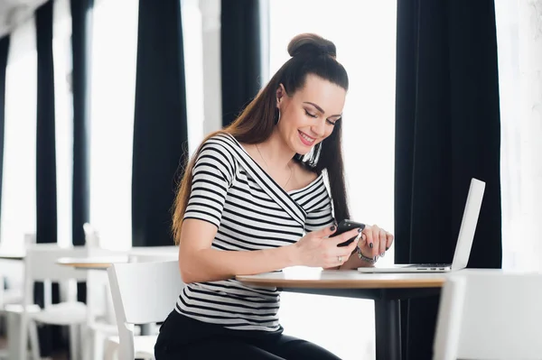 Lachende aantrekkelijke vrouw leest sms-bericht op mobiele telefoon bij restaurant. — Stockfoto