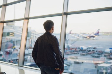 Genç adam Havaalanı iç şehir manzaralı ve bir uçak tarafından uçan konseptiyle seyahat.