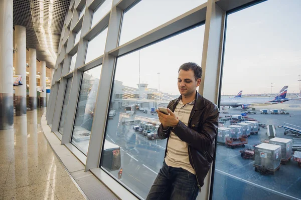 Porträt eines attraktiven jungen Mannes, der geht und auf sein Handy schaut — Stockfoto