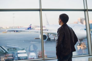 Genç adam Havaalanı iç şehir manzaralı ve bir uçak tarafından uçan konseptiyle seyahat.