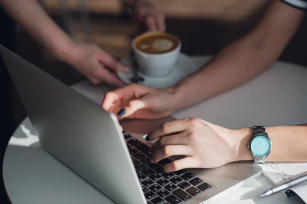 Bovenaanzicht van het vrouwtje haar laptop gebruikt in een café. Overhead schot van jonge vrouw zitten aan een tafel met een kopje koffie en mobiele telefoon surfen op het net op haar laptopcomputer. — Stockfoto