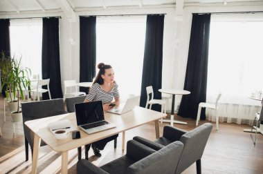 Genç çekici kadın onu laptop ile bir kafede masada oturan ve düşünceli uzağa bakarken çalışma.