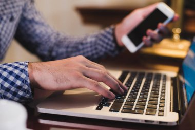 Büyük akıllı telefon kablosuz için ahşap masa başında oturan teknolojisini kullanarak işadamı bağlanırken holding erkek eller yukarı kapatın