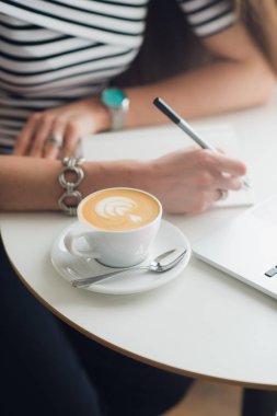 Yakın çekim elleri boş defter yanında kahve ile üzerinden bir kalem tutan kadın. Üstten Görünüm kompozisyon. İşyeri ofis kadın.