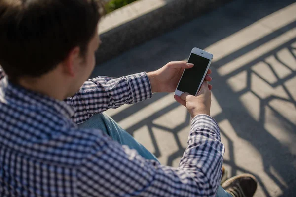 Mann benutzt sein Handy im Freien, während er auf einer Treppe sitzt, Nahaufnahme — Stockfoto