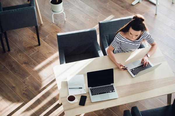 Visão superior de uma mulher de negócios adulta sentada à mesa e fazendo anotações no caderno. Na mesa está laptop, smartphone e xícara de café. Estudante aprendendo online. Blogueiro . — Fotografia de Stock