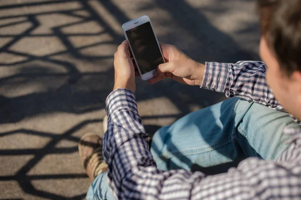 Mann benutzt sein Handy im Freien, während er auf einer Treppe sitzt, Nahaufnahme — Stockfoto