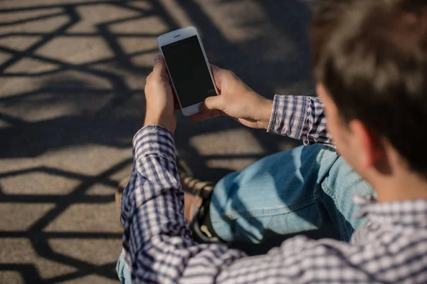 Mann benutzt sein Handy im Freien, während er auf einer Treppe sitzt, Nahaufnahme — Stockfoto