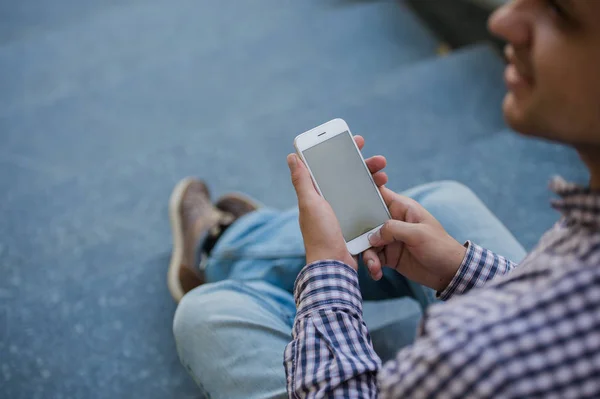 Mann benutzt sein Handy im Freien, während er auf einer Treppe sitzt, Nahaufnahme — Stockfoto