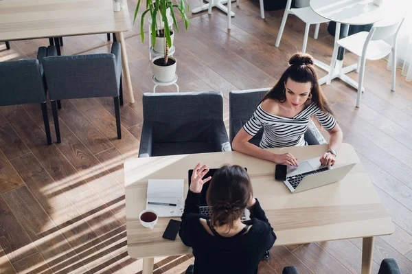 Εναέρια βολή των γυναικών επιχειρηματιών που εργάζεται σε μια καφετέρια. Δύο συνεργάτες κάθεται στο γραφείο σε γραφείο και την αλληλεπίδραση. — Φωτογραφία Αρχείου