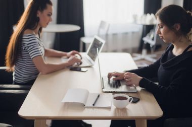 Başlangıç iş kavramı ile modern parlak ofis iç çalışma dizüstü bilgisayarlarda ve tablet bilgisayarlar yeni yaratıcı proje ve beyin fırtınası, hava Üstten Görünüm'de iki genç kız.