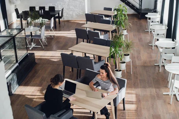 Twee vrouwen zijn op zoek naar elkaar en lachen met een laptop voor hen. — Stockfoto