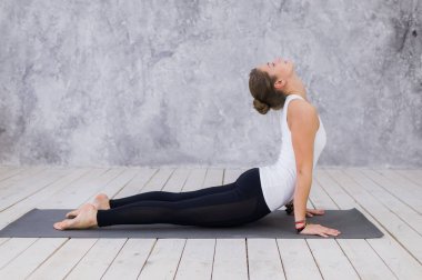 Güzel genç kadın kapalı çalışma dışarı, beyaz duvarlar ile oda yoga egzersiz yaparak, aşağı doğru bakan köpek poz, adho mukha svanasana güneş selamlama poz, tam uzunlukta, yan görünüm