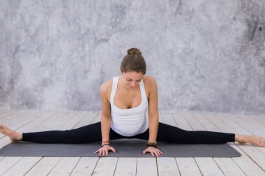 Bacaklar, yoga sınıf germe sportif genç bir kız. Sicim içinde oturan sarışın kadın