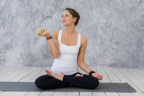 Caucasian beautiful healthy athletic sportive girl eat green apple after the training and looking at camera — Stock Photo, Image