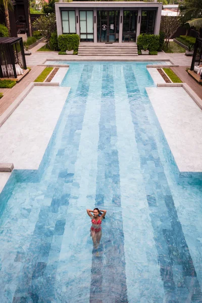 Foto aérea vista superior de um modelo sexy sedutor em roupa de banho branca está desfrutando de relaxar na piscina do hotel durante seu fim de semana de verão. Mulher de moda incrível em biquíni ter descanso spa de luxo — Fotografia de Stock