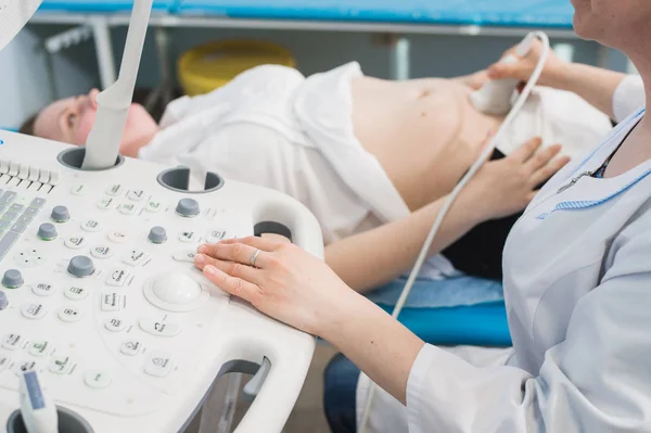 Zblízka inkognito lékaře pomocí ultrazvukové zařízení pro vyšetření těhotné ženě a na tlačítka speciálních počítačových. Žena diagnostikování v klinice — Stock fotografie