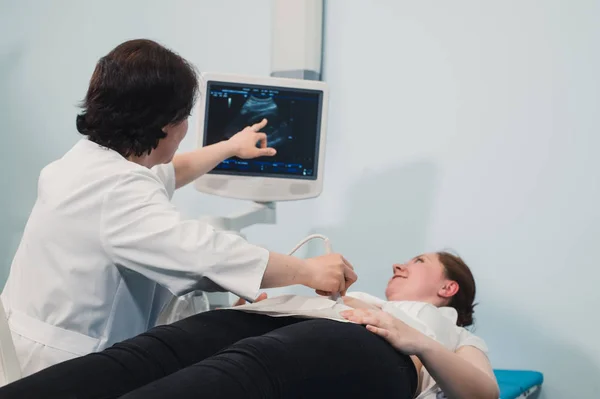 Lékař pomocí ultrazvuku a vyšetření žaludku těhotná žena. — Stock fotografie