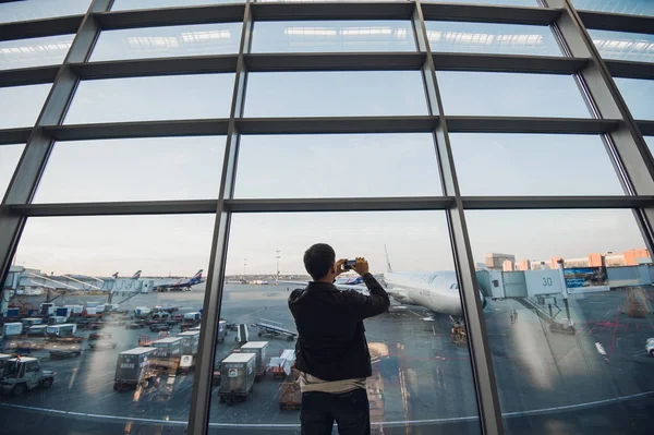 Traveler with mobile phone at the airport taking picture of his aircraft. Air Traffic Control facilities at the background — Stock Photo, Image