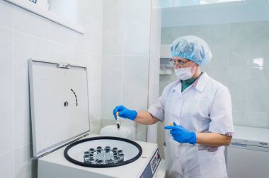 Üst düzey bir kadın kimyacı bazı örnek kan tüpler içinde bir santrifüj için bazı test laboratuarında kurma closeup.