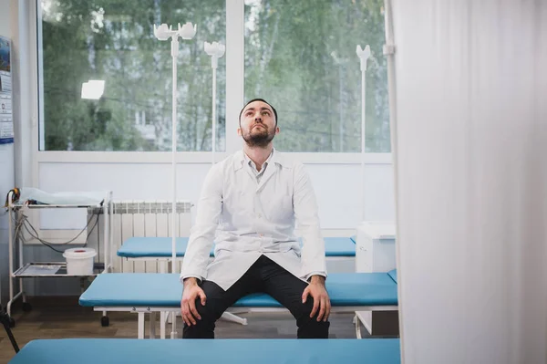 Médico cansado sentado solo en la sala del hospital . — Foto de Stock