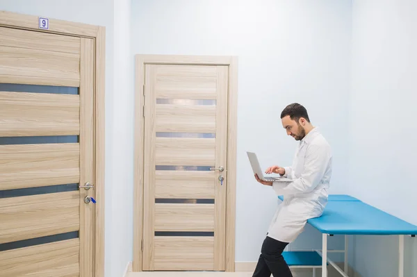 Médico especialista en el pasillo de su clínica con su portátil — Foto de Stock