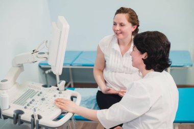 Doktor gösteren bebek ultrason görüntüsünün bilgisayara hamile kadına