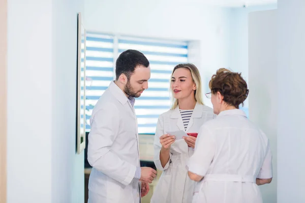 Médico maduro discutiendo con enfermeras en un hospital de pasillo. Doctor discutiendo el estado del caso del paciente con su personal médico después de la operación . — Foto de Stock