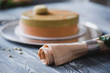 Badem dacquoise, ahududu confit, gevrek katmanla karamelize fındık ve ahududu tozu ile sarı puding kek fırından yeni çıkmış, ahşap masaya servis bağlı olarak bitter çikolata mousse