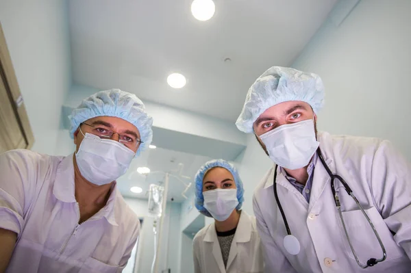 Debajo de la vista de cirujanos sosteniendo instrumentos médicos en las manos y mirando al paciente — Foto de Stock