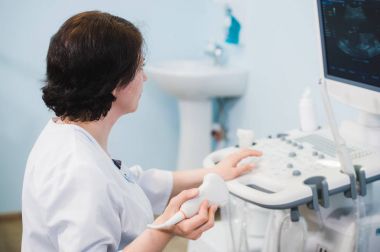 Ultrason tarayıcı kullanarak mutlu olgun kadın doktor. Echography makine