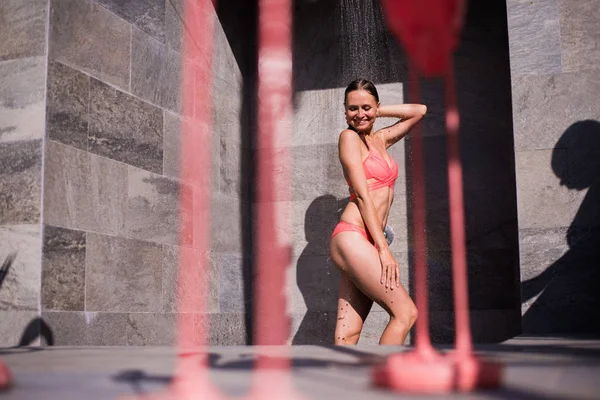 Chuveiro na praia. Dois bela mulher ajuste tomando banho na piscina. Meninas com corpo sexy em roupa de banho sob a água, lavar o cabelo, limpar o corpo e a pele ao ar livre no luxuoso Spa Resort em — Fotografia de Stock