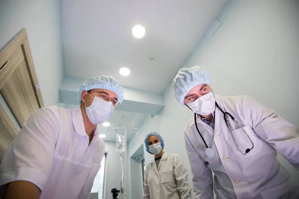 Debajo de la vista de cirujanos sosteniendo instrumentos médicos en las manos y mirando al paciente — Foto de Stock