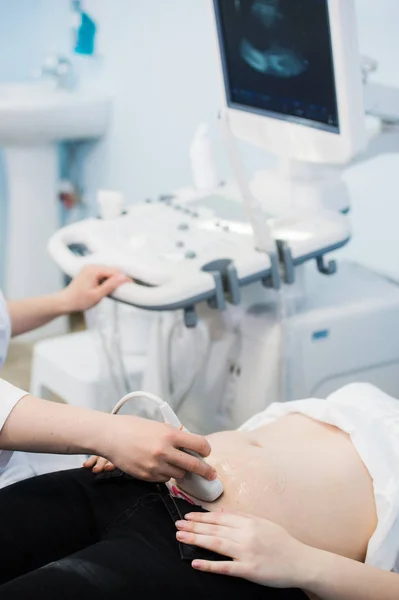 Närbild av läkare flytta ultraljudssond på gravid kvinnas mage på sjukhus — Stockfoto
