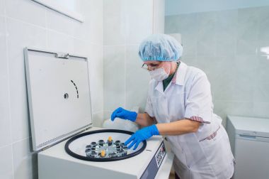 Üst düzey bir kadın kimyacı bazı örnek kan tüpler içinde bir santrifüj için bazı test laboratuarında kurma closeup.