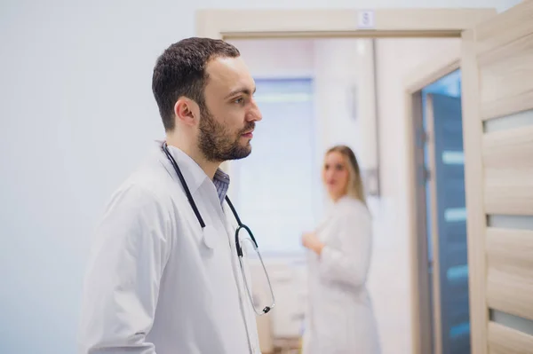 Pensive young doctor in white coat holding diagnosis in hospital, caring doctor concept — Stock Photo, Image