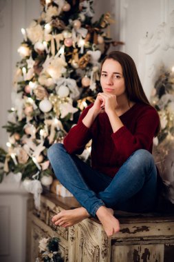 Noel hediyesi olan bir kadın klozete oturmuş Noel için dekore edilmiş. Arkadaki fidan ağacı