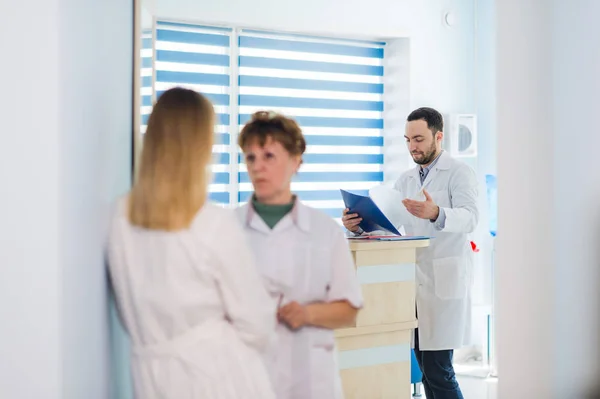 Médico maduro discutiendo con enfermeras en un hospital de pasillo. Doctor discutiendo el estado del caso del paciente con su personal médico después de la operación . —  Fotos de Stock