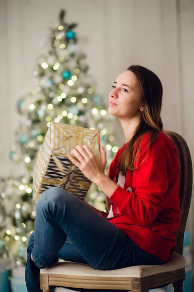 家でクリスマスツリーに座って贈り物と美しい女性の肖像 — ストック写真