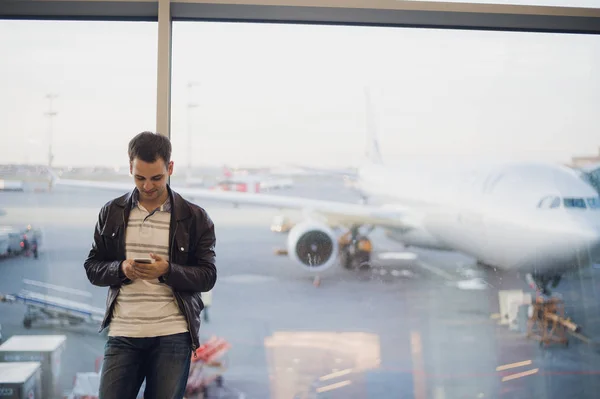 Young business man in airport using smartphone .