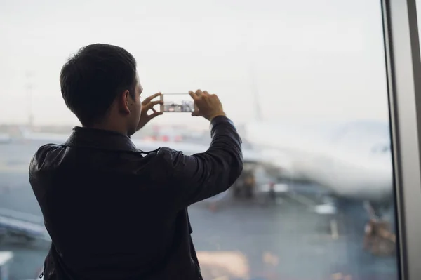 Man hand ta bild av flygplan med hjälp av mobiltelefon. Turism-konceptet Foto — Stockfoto