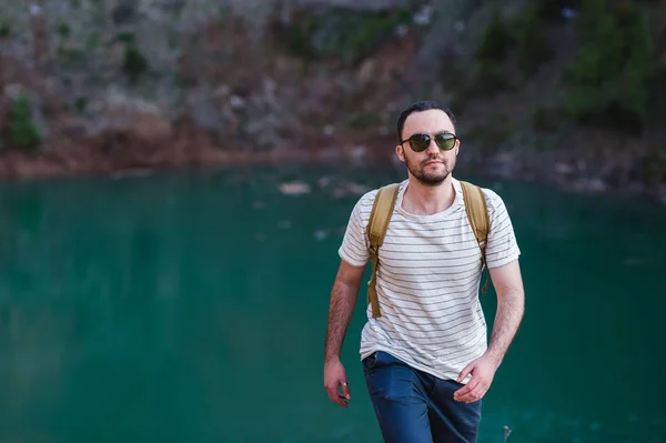 Barbudo modelo hombre posa junto a un lago de agua verde . — Foto de Stock