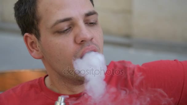 Close up retrato de um homem exalando vapor usando cigarro eletrônico em câmera lenta — Vídeo de Stock