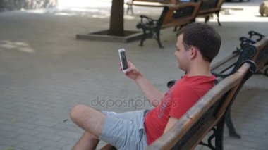 Açık havada bankta otururken onun arkadaş ya da kardeş telefonda Sohbet yakışıklı adam video