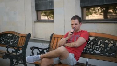 Vaper duman elektronik sigara bir bankta otururken açık