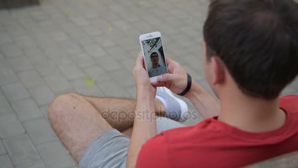 Primo piano di una mano maschile in possesso di uno Smart Phone durante una videochiamata con il suo amico — Video Stock
