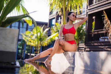 Kırmızı bikini giyen güzel ince seksi kadın relax açık su havuzu üzerinde resort yakınındaki