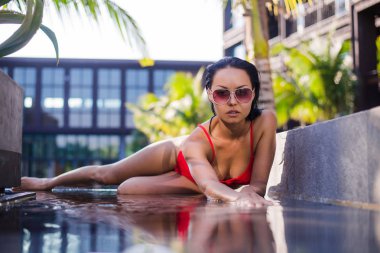 havuz başında poz güzel kadın modeli. açık havada ateş sıcak renkler, tonda. Yatay.