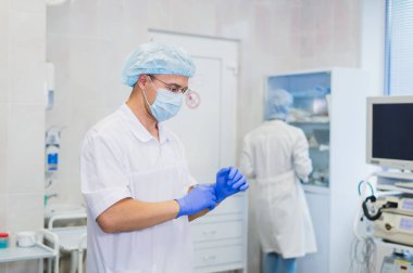 Operasyon için hazırlık sırasında genç bir doktor. Asistan cerrah operasyon odasında hastanede cerrahi maske.