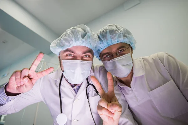 Dos médicos alegres por encima de la cámara muestran la mano firmar la paz — Foto de Stock